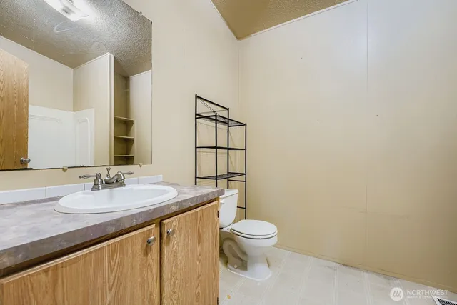 a bathroom with a granite countertop sink mirror vanity and toilet