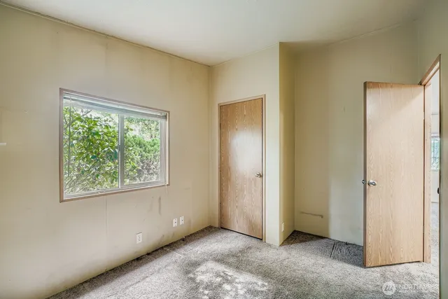 a view of an empty room with window and closet area