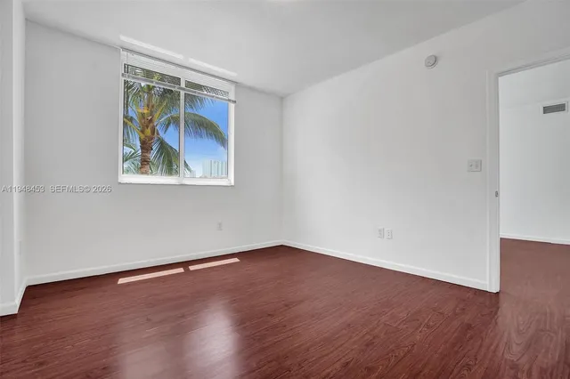 an empty room with wooden floor and window