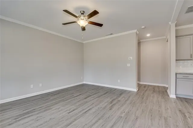 an empty room with wooden floor and a ceiling fan