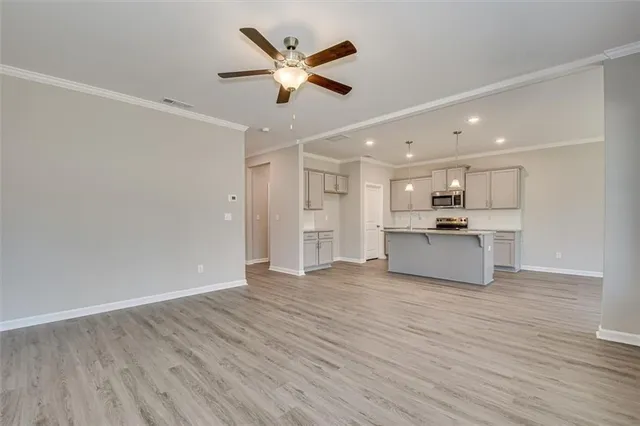 a view of an empty room with wooden floor and a ceiling fan