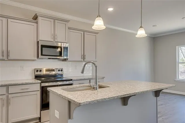 a kitchen with stainless steel appliances granite countertop a sink a stove a microwave and cabinets