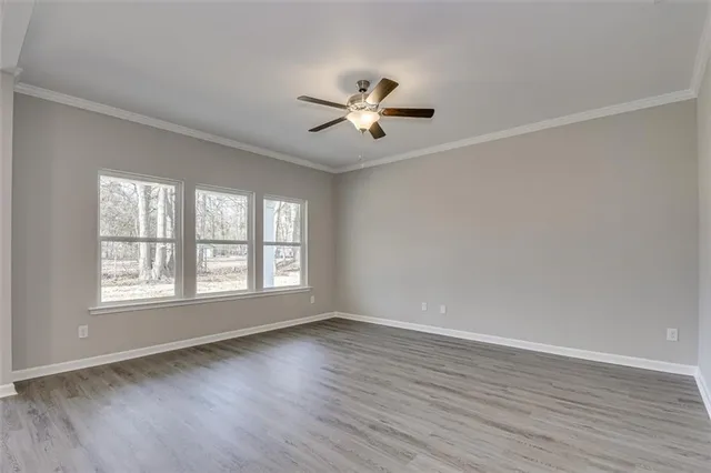 an empty room with wooden floor fan and windows