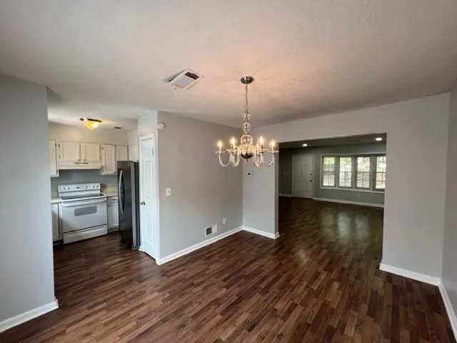 a view of a room with wooden floor kitchen and windows