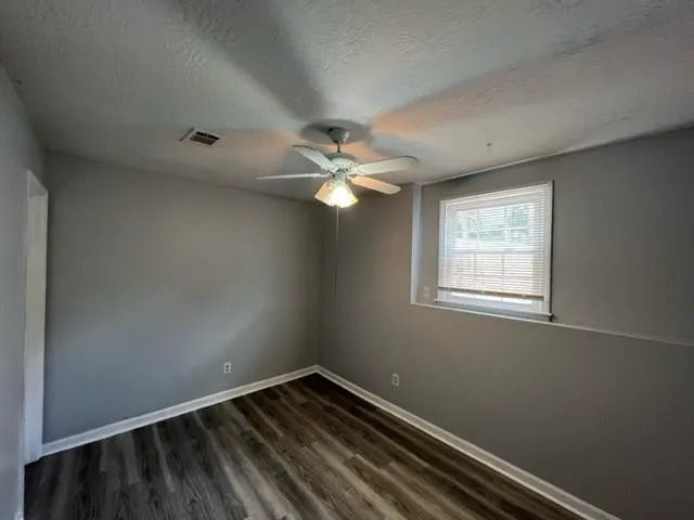 an empty room with a window and a fan