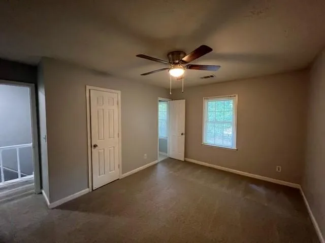 an empty room with a chandelier fan and windows