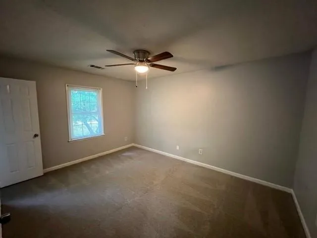 an empty room with windows and fan