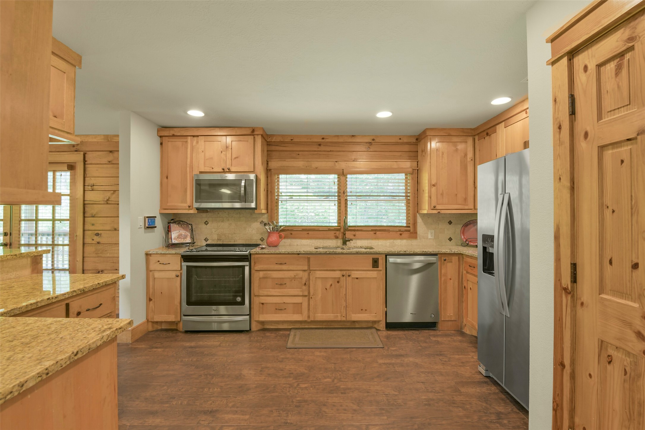 91 Bluejay Way Cleveland, TX 77327 - Photo 23 of 50 a large kitchen with a refrigerator a stove top oven a sink dishwasher and wooden cabinets