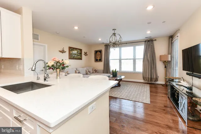 a large white kitchen with wooden floor and a sink