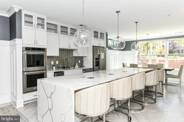 a kitchen with stainless steel appliances kitchen island granite countertop a table chairs and a refrigerator