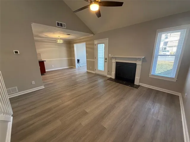 an empty room with wooden floor fan and windows