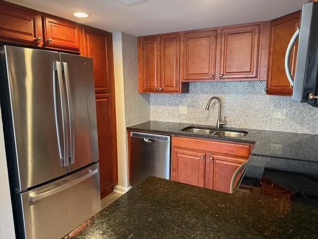 a kitchen with granite countertop a sink stove and microwave