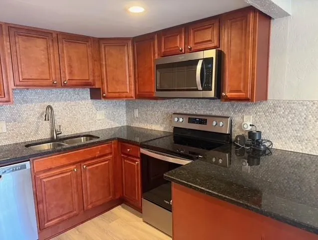 a kitchen with stainless steel appliances granite countertop a sink stove and refrigerator