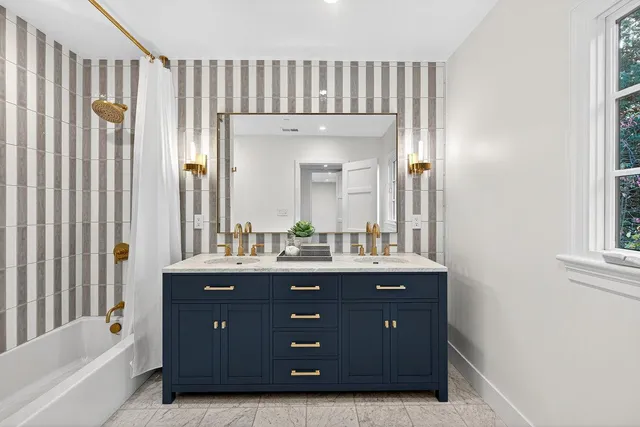 a spacious bathroom with a granite countertop sink a mirror and a bathtub