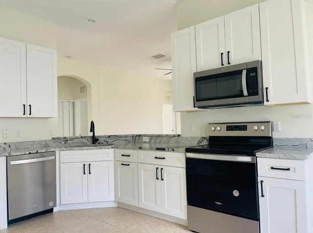 a kitchen with granite countertop white cabinets and black appliances