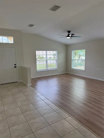 a view of an empty room with a window and wooden floor