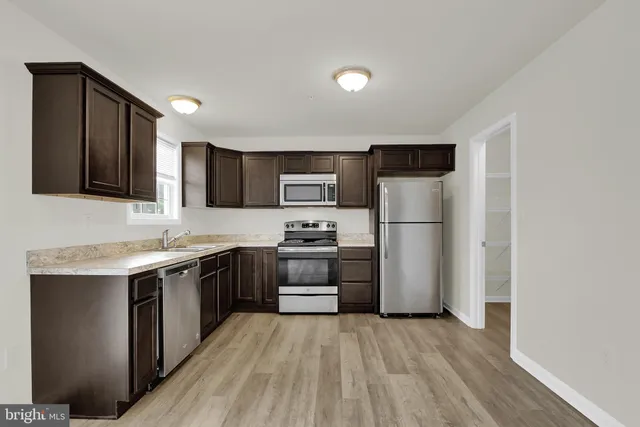 a kitchen with stainless steel appliances granite countertop white cabinets a sink a stove a refrigerator and a microwave