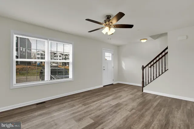 a view of empty room with wooden floor and fan