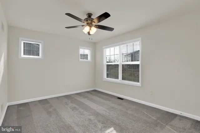 an empty room with windows and fan