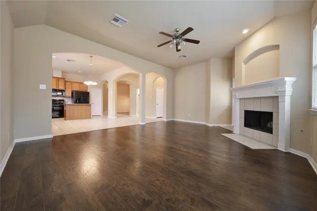an empty room with wooden floor a fireplace and windows