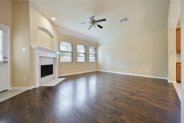 an empty room with wooden floor fireplace and windows