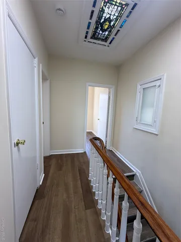 a view of a hallway to a livingroom with wooden floor and stairs