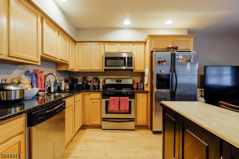 5 Maple Avenue Union, NJ 07088 - Photo 6 of 11 a kitchen with stainless steel appliances kitchen island granite countertop a refrigerator a stove top oven and sink with wooden floor