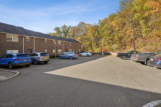 a view of road with card parked on side and retail shops