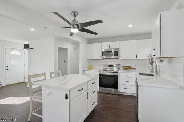 a kitchen with granite countertop a sink stainless steel appliances and white cabinets