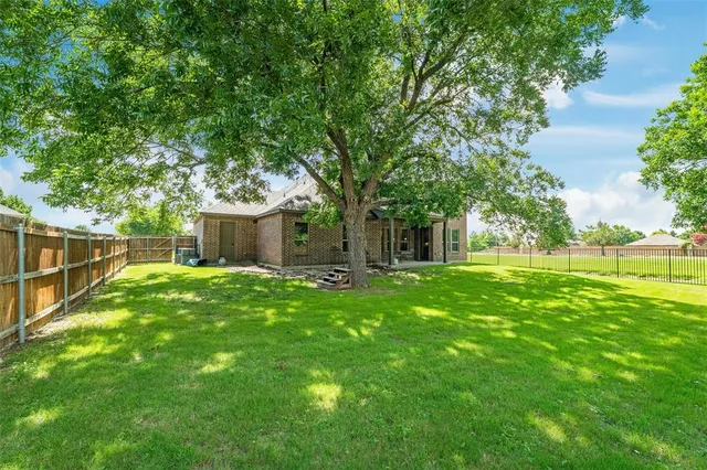 a backyard of a house with table and chairs and a large tree