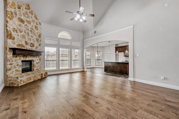 an empty room with wooden floor fireplace and windows