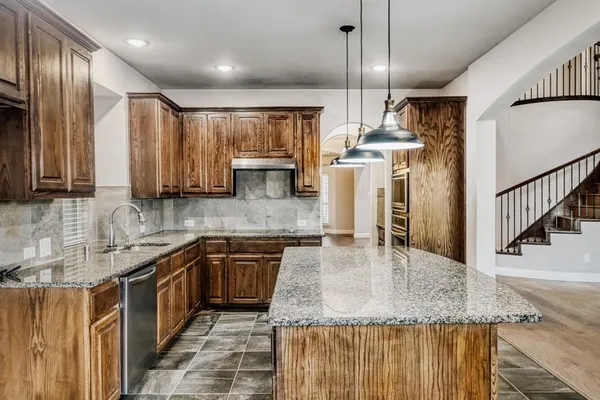 a kitchen with stainless steel appliances granite countertop a sink a stove and a wooden cabinets
