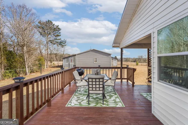 a view of a roof deck with table and chairs a barbeque with wooden floor and fence