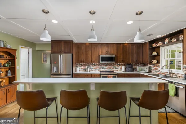 a kitchen with stainless steel appliances a dining table chairs refrigerator and microwave
