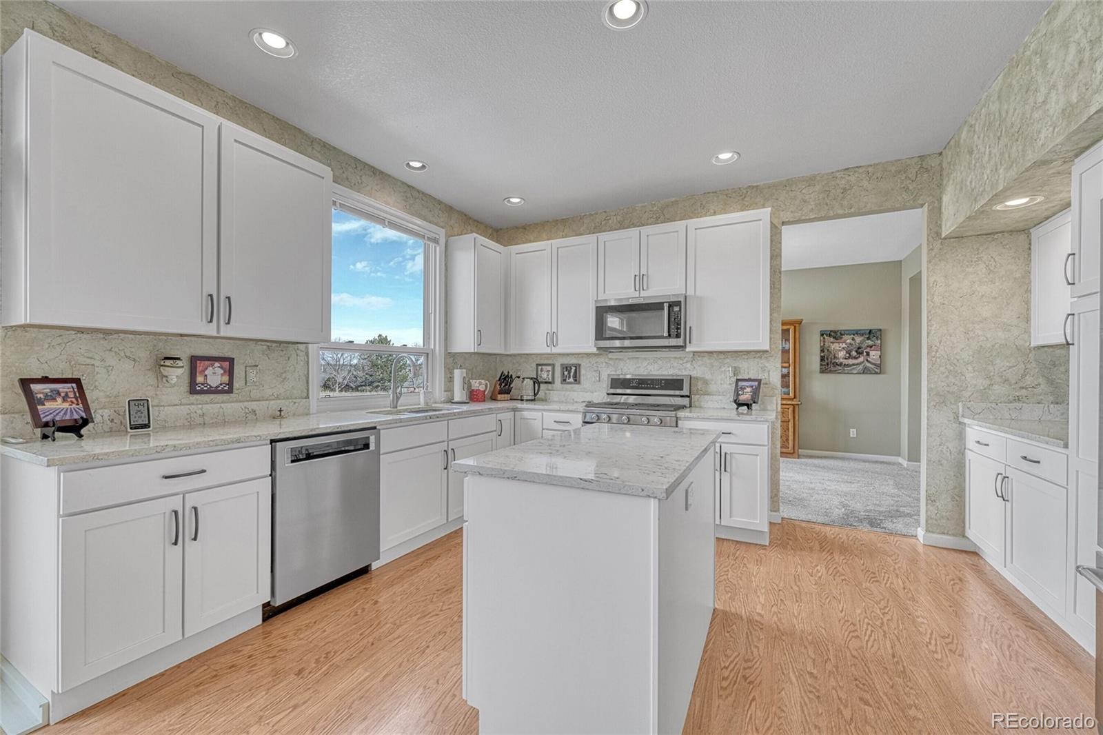 9247 Sugarstone Circle Highlands Ranch, CO 80130 - Photo 11 of 48 a kitchen with stainless steel appliances granite countertop a stove top oven a sink a refrigerator and white cabinets