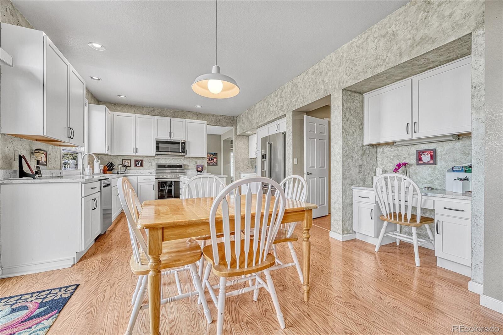 9247 Sugarstone Circle Highlands Ranch, CO 80130 - Photo 8 of 48 a kitchen with stainless steel appliances granite countertop a dining table chairs refrigerator and sink