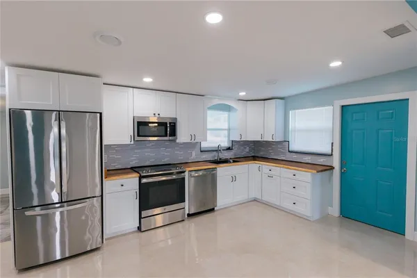a large kitchen with stainless steel appliances granite countertop a stove a sink and a microwave