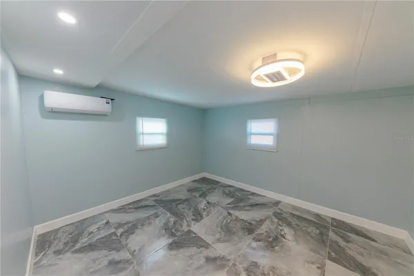 an empty room with a fan & a window