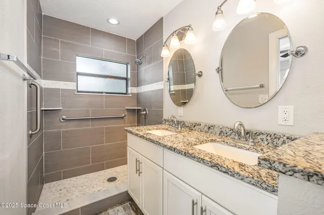 a bathroom with a granite countertop sink a mirror and shower