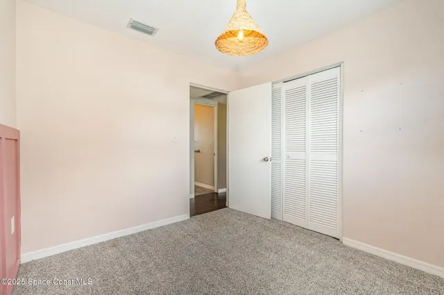an empty room with a door and a chandelier fan