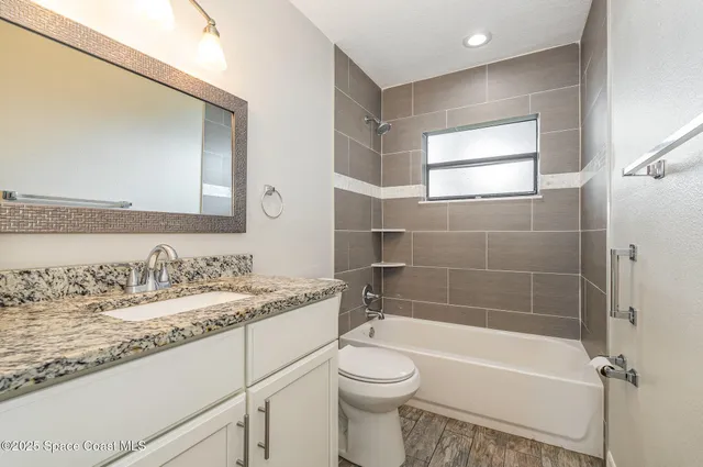 a bathroom with a granite countertop sink toilet and shower