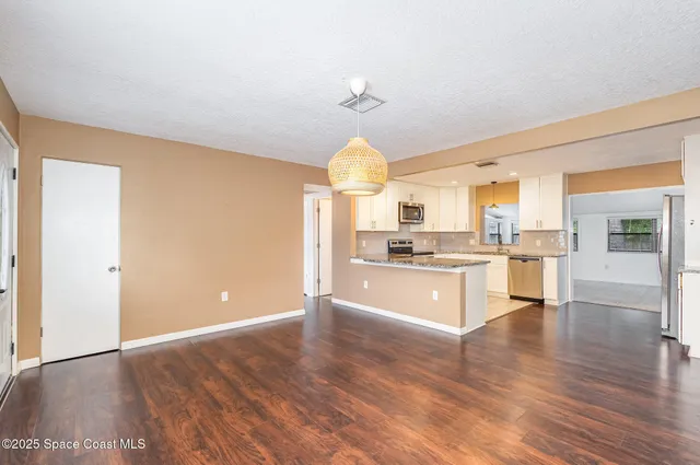 a large kitchen with white cabinets stainless steel appliances and wooden floor