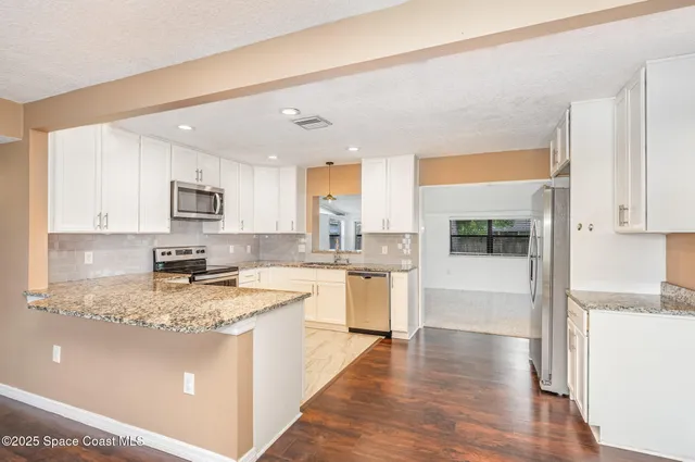 a kitchen with a refrigerator a stove a sink and white cabinets with wooden floor