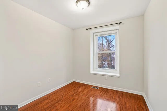 a view of an empty room with wooden floor and closet