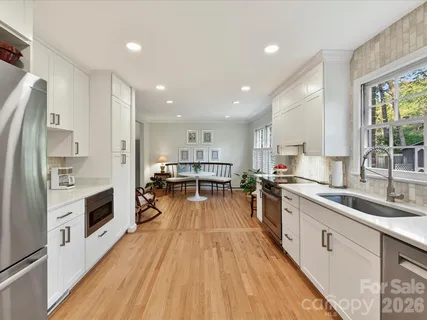 a kitchen with stainless steel appliances hardwood floor sink stove and wooden cabinets