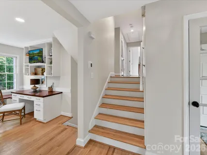 a view of a hallway with wooden floor and furniture