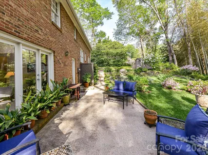 a view of a patio with table and chairs potted plants and large tree