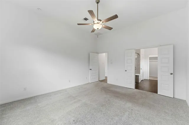 a view of a room with a ceiling fan and carpet