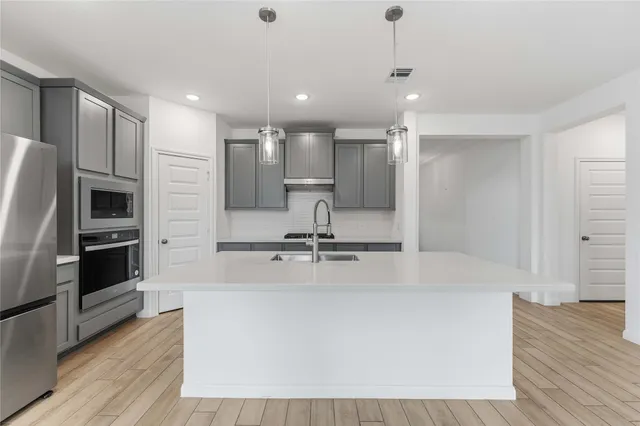 a large kitchen with stainless steel appliances a large counter top a stove and a refrigerator