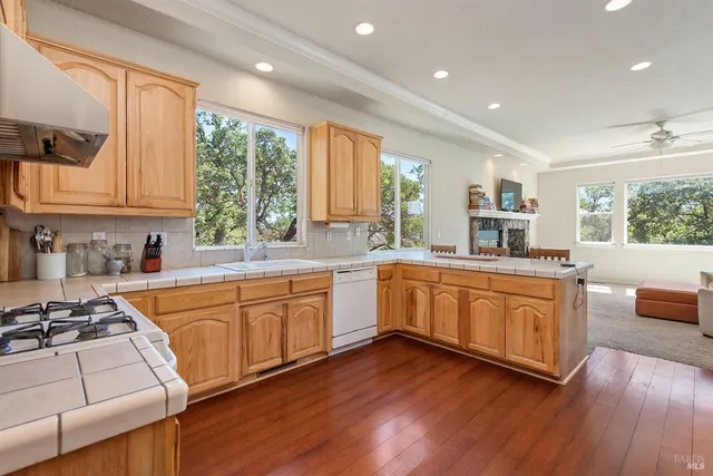 a kitchen with stainless steel appliances granite countertop wooden floors a stove a sink and a window